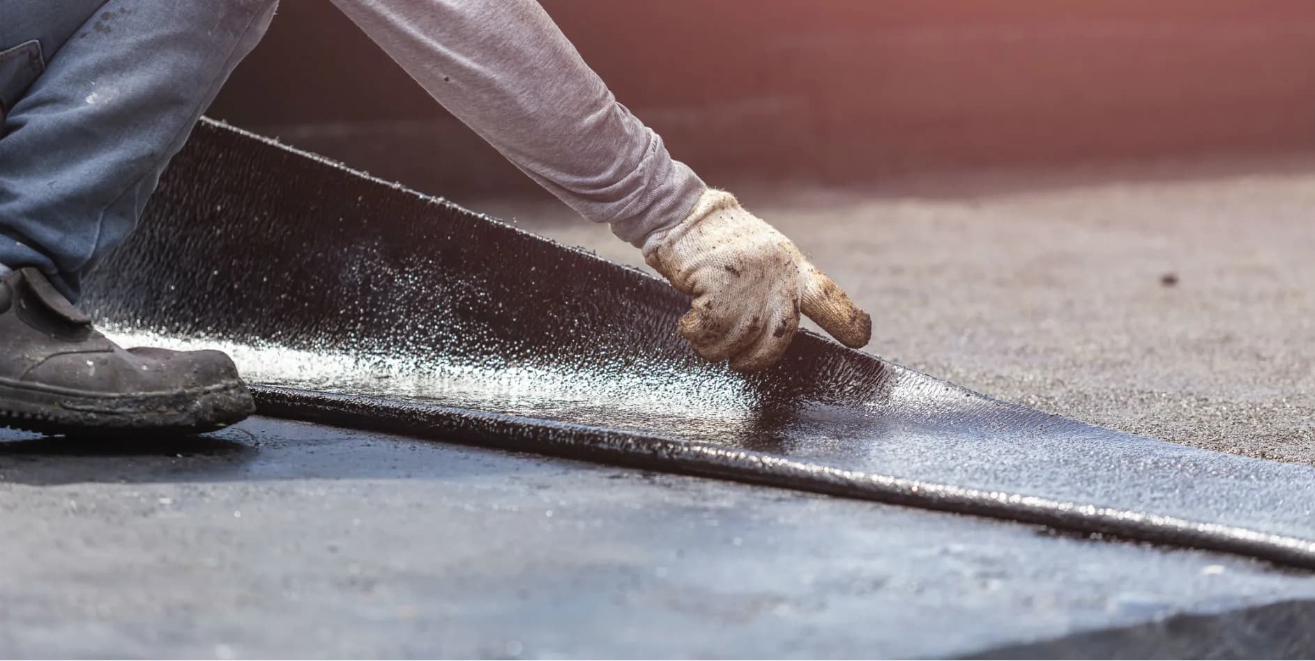 A roofer carefully laying waterproof roofing material